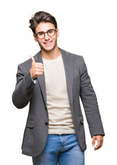 Young business man wearing glasses over isolated background doing happy thumbs up gesture with...