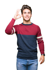 Young handsome man over isolated background smiling positive doing ok sign with hand and fingers. Successful expression.