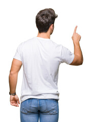 Young handsome man wearing white t-shirt over isolated background Posing backwards pointing behind...