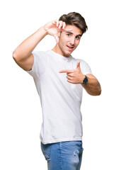 Young handsome man wearing white t-shirt over isolated background smiling making frame with hands and fingers with happy face. Creativity and photography concept.