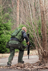 Man in camouflage runs with rifle during assault