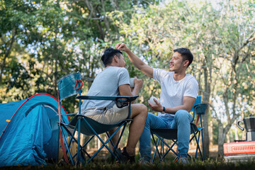 Male gay couple asian traveling with tent camping outdoor and various adventure lifestyle hiking active summer vacation. drinking coffee and talking together