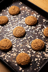 Craft and rustic four oatmeal cookies. Dark food aesthetics, black background with several oat flakes.