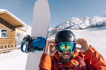Laughing snowboarder on the slope of ski resort putting on  mask for skiing