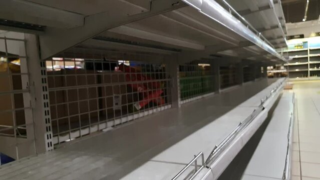 Supermarket with empty shelves for goods. Food collapse. Camera movement from top to bottom. Selective focus.