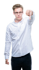 Naklejka premium Young handsome blond man looking unhappy and angry showing rejection and negative with thumbs down gesture. Bad expression.