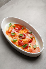 Delicious Italian ravioli pasta with tomato sauce, parmesan cheese and fresh basil leaves on a gray background