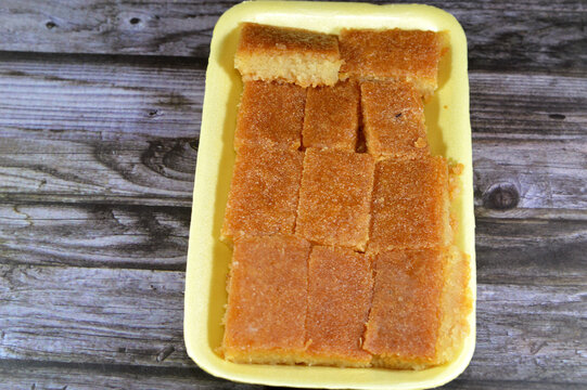 Plain basbosa or basbusa cut into pieces with honey sugary syrup on it, Basbusa is a middle eastern dessert that is usually baked in Ramadan month, Arabian sweet cuisine background, selective focus