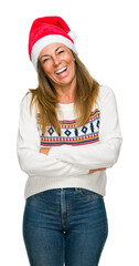 Middle age adult woman wearing winter sweater and chrismat hat over isolated background happy face smiling with crossed arms looking at the camera. Positive person.