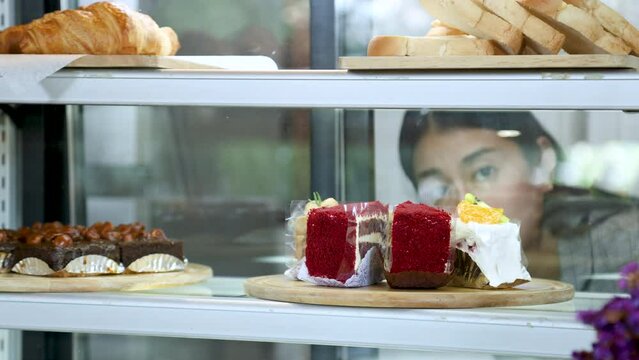 Closeup female hand pointing cake or buying from bakery cabinet in eatery restaurant retails small business coffee shop selling multi products, coffee beverage, bakery, start-up cafe business owner