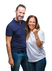 Naklejka premium Middle age hispanic casual couple over isolated background smiling with happy face looking and pointing to the side with thumb up.