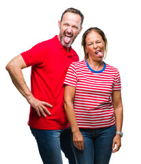 Fototapeta premium Middle age hispanic couple in love over isolated background sticking tongue out happy with funny expression. Emotion concept.
