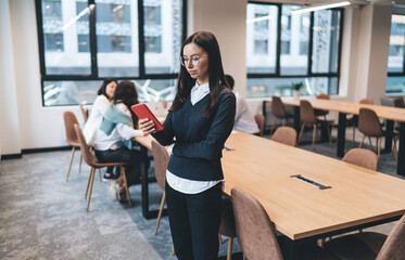 Focused woman browsing smartphone in modern workspace
