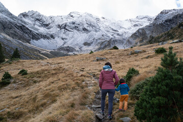 Back view of a mother and her little daughter hiking in Néouvielle mountains in french Pyrenees during a winter day.