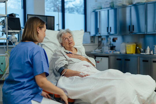 Nurse taking care of senior patient in intensive care unit. Senior woman after stroke, heart attack recoverying, lying in hospital bed.