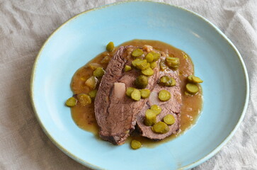 beef stew with pickled green cucumber and serving on a blue plate, czech food