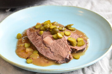 beef stew with pickled green cucumber and serving on a blue plate, czech food