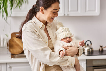 Obraz na płótnie Canvas beautiful joyous woman in cozy homewear posing with her cute newborn baby boy, modern parenting
