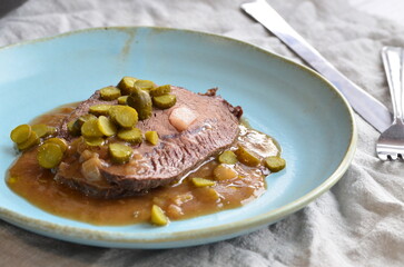 beef stew with pickled green cucumber and serving on a blue plate, czech food