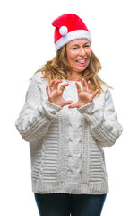 Middle age senior hispanic woman wearing christmas hat over isolated background disgusted expression, displeased and fearful doing disgust face because aversion reaction. With hands raised.