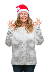 Obraz na płótnie Canvas Middle age senior hispanic woman wearing christmas hat over isolated background relax and smiling with eyes closed doing meditation gesture with fingers. Yoga concept.
