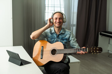 Obraz premium The guy in live online live records podcasts, plays guitar. He communicates with people, smiles, and runs his own music blog.