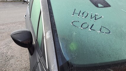 Che freddo scritto su un'auto con il parabrezza coperto di ghiaccio.