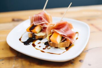 prosciutto and melon on crusty bread with balsamic glaze on a plate