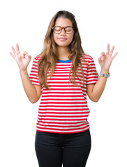 Young beautiful brunette woman wearing glasses and stripes t-shirt over isolated background relax and smiling with eyes closed doing meditation gesture with fingers. Yoga concept.