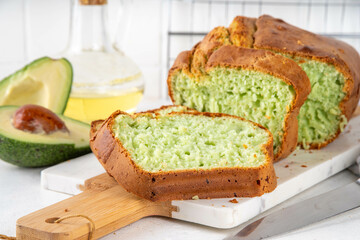 Homemade avocado loaf of bread, keto diet recipe, healthy alternative food idea, on white kitchen background with fresh avocado, copy space