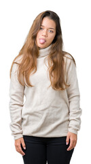 Young beautiful brunette woman wearing turtleneck sweater over isolated background sticking tongue out happy with funny expression. Emotion concept.