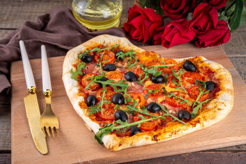 Valentines day heart shaped pizza, love and dating concept with mozzarella. tomatoes, pepperoni and arugula on vintage wooden table background top view copy space