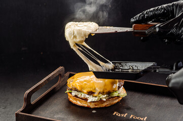 Juicy fresh burger with melted mozzarella cheese on a dark background