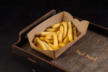 Tasty fast food, fried french fries takeaway in paper box on background