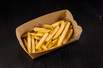 Tasty fast food, fried french fries takeaway in paper box on background