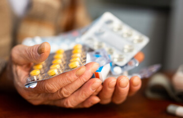 Many different pills and medicines in the hands of an old man
