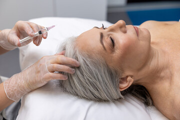 Obraz na płótnie Canvas Mature woman having filler injections at beauty clinic