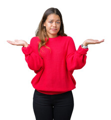 Young beautiful brunette woman wearing red winter sweater over isolated background clueless and...