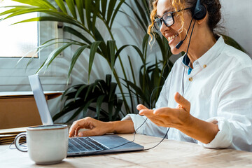 Curly woman with glasses using laptop, communicating on Internet with client in home, Cozy working...
