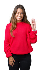 Obraz na płótnie Canvas Young beautiful brunette woman wearing red winter sweater over isolated background Waiving saying hello happy and smiling, friendly welcome gesture