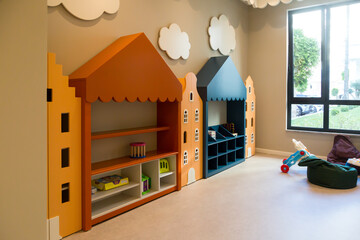 Interior of a spacious children's room with furniture and a large window.