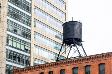 Low angle view of a traditional water tank on the roof of an old brick building in a downtown district on a cloudy spring day