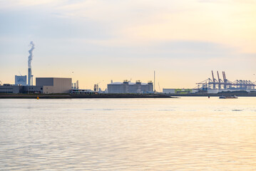 Industrial buildings, fuel storage tanks and gantry cranes at a major seaport at sunset in summer