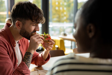 Young couple having pizza in a cafe and looking enjoyed