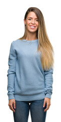 Beautiful young woman wearing sweater and jeans with a happy face standing and smiling with a confident smile showing teeth