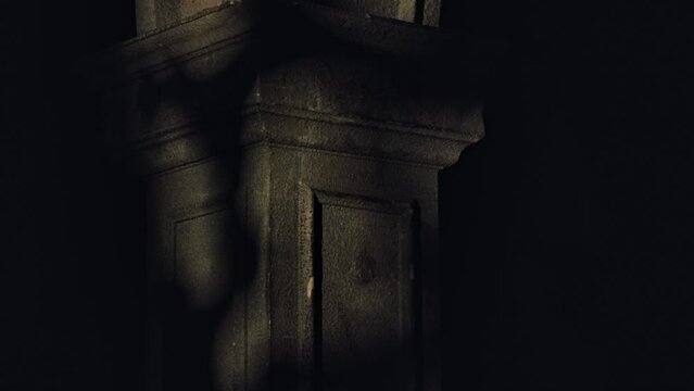 Textured stone old arch in a dark room of a Gothic church. Contrasting artistic shadows. Scary church interior