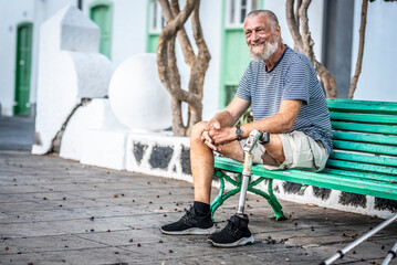 Elderly man with prosthetic leg. left rests sitting on a park bench. Spending a relaxing afternoon....