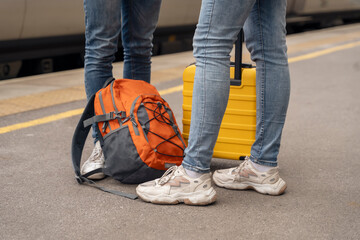 Travelers with a backpack and a .suitcase waiting for a train on the platform at a train station....