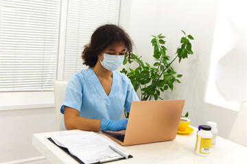 Doctor working on laptop computer in clinic office during pandemic