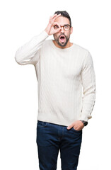 Young handsome man wearing glasses over isolated background doing ok gesture shocked with surprised face, eye looking through fingers. Unbelieving expression.